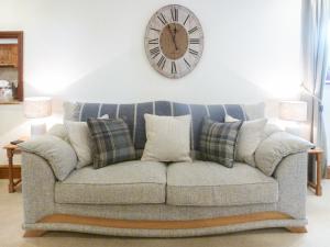 Un sofá con almohadas y un reloj en la pared. en Anneth Lowen, en Pentewan 8 fotos más