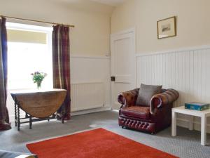 a living room with a chair and a table at The Bothy - Uk33907 in Rattray