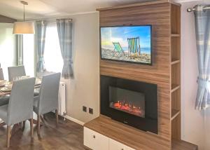 ein Wohnzimmer mit einem Kamin und einem Tisch mit Stühlen in der Unterkunft Golden Palm Resort in Chapel Saint Leonards