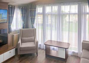 ein Wohnzimmer mit einem Stuhl, einem Tisch und einem TV in der Unterkunft Golden Palm Resort in Chapel Saint Leonards + 39 Fotos