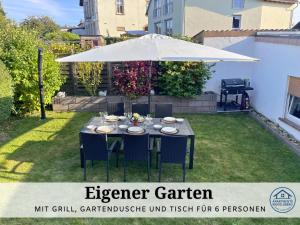 a table with an umbrella in a yard at Apartment Rosie - Rustikal und top ausgestattet und ideal für Gruppen bis 6 Personen und Hund, egal ob Familie, Kollegen oder Freunde, 85qm mit Garten und eigener Garage in Riegelsberg