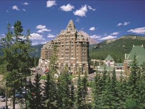 ein großes Gebäude mit Bäumen vor einem Berg in der Unterkunft Fairmont Banff Springs in Banff