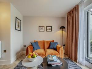 an orange couch in a living room with a table at Restharrow - Uk49244 in Whitstable