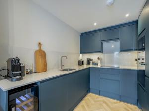 a blue kitchen with white counters and blue cabinets at Restharrow - Uk49244 in Whitstable