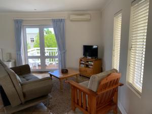 a living room with a couch and a chair and a television at Apartment on Thesen Island in Knysna
