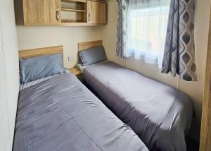 two beds in a small room with a window at Ty Gwyn Park in Abergele +10 photos