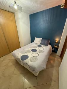 a bedroom with a bed with a blue wall at Joli appartement cozy in Mercury