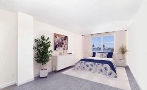 a white bedroom with a bed and a potted plant at Bright Two-Bedroom Condo with Intracoastal Views in Palm Beach