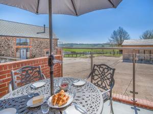 a table with an umbrella and a plate of food at The Stables - Uk49089 in Crediton
