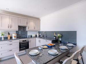 a kitchen with white cabinets and a table and chairs at The Stables - Uk49089 in Crediton