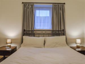 a bedroom with a bed with a window and two lamps at Coast To Coast Cottage in Cleator Moor