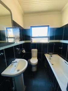 a bathroom with a sink and a toilet and a tub at Solovina Guest House in Foso