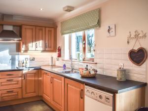 a kitchen with wooden cabinets and a sink and a window at Trelaw - Uk41532 in Ochiltree +14 photos