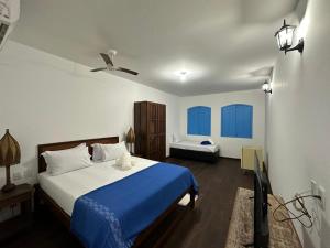 1 dormitorio con 1 cama azul y blanca y TV en San Sebastian Taipu de Fora, en Maraú