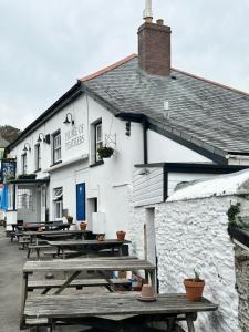 a row of picnic tables in front of a building at Plume of Feathers in Porthscatho