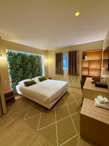 a bedroom with a large bed and a large window at Hôtel Le Mistral in Porto-Vecchio