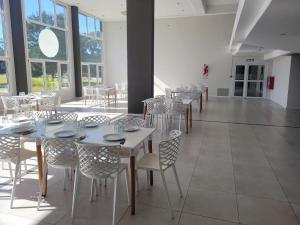 a dining room with tables and chairs and windows at Suite Rincon del Sol in Pinamar