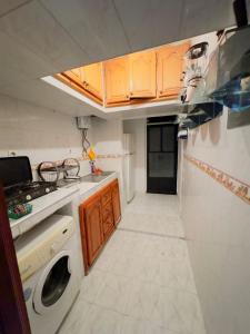 a small kitchen with wooden cabinets and a washer and dryer at Julie Airport Boarding Apartment in Marrakech
