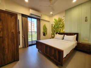 a bedroom with a large bed and a large window at Bright Candolim 1BHK with Pool, Gym, Parking - 5 Minutes to Beach in Candolim +16 photos