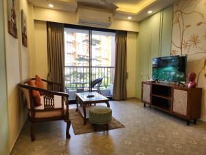 a living room with a tv and a couch and a table at Bright Candolim 1BHK with Pool, Gym, Parking - 5 Minutes to Beach in Candolim