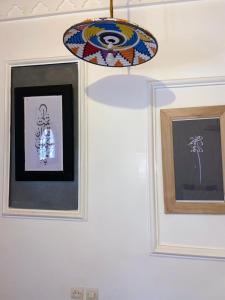 two framed pictures on a wall with a chandelier at Hotel Atlas Gorge Dades in Boumalne