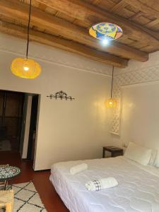 a bedroom with a white bed and two lights at Hotel Atlas Gorge Dades in Boumalne