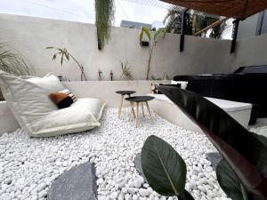 a patio with a white couch and some plants at Le Veloutier by Hestia LCD, 1 chbre avec SPA privé in Bois de Nèfles