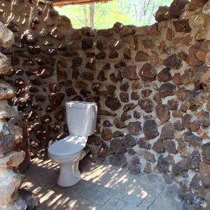 Un inodoro blanco frente a una pared de piedra. en Maguni Campsite, en Mupapama