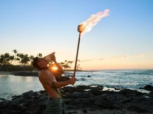 a man standing on the beach holding a stick at Fairmont Orchid in Waikoloa