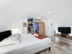 a bedroom with a white bed and a flat screen tv at Love Room Beaumont Sauna et Balnéo in Beaumont +8 photos