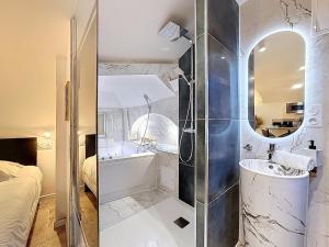 a bathroom with a tub and a sink and a mirror at Love Room Beaumont Sauna et Balnéo in Beaumont