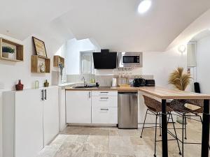 a kitchen with white cabinets and a wooden table at Love Room Beaumont Sauna et Balnéo in Beaumont