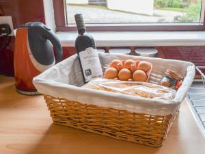 a basket with a bottle of wine and eggs at Pine Marten Cottage in Ballachulish