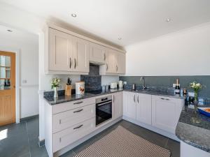 a kitchen with white cabinets and granite counter tops at The Stables - Uk49089 in Crediton