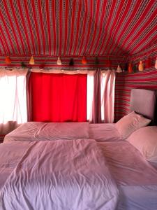 a bedroom with a large bed with a red curtain at Golden Camp Tours in Wadi Rum +17 photos