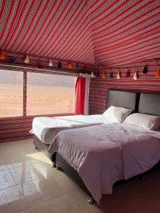 a bedroom with two beds and a red wall at Golden Camp Tours in Wadi Rum