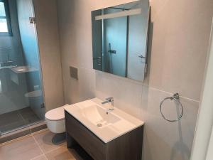 a bathroom with a sink and a toilet and a mirror at Erniesa in Accra