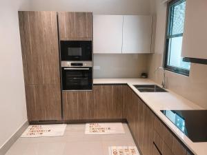 a kitchen with wooden cabinets and a microwave at Erniesa in Accra