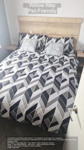a bed with a black and white comforter and pillows at Parkdean Camber Sands sleeps 8 Pet Friendly - ref-ww242 in Camber