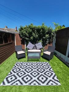 滨海戈尔斯顿Cosy Pet Friendly Holiday House in Gorleston - five minutes to beach的院子里的一组椅子和一块地毯