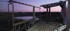 a wooden deck with lights and a body of water at Casa Campo in Cufré