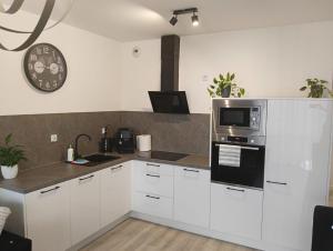 a kitchen with white cabinets and a microwave at Apartament MajaHouse 2 in Nowa Sól