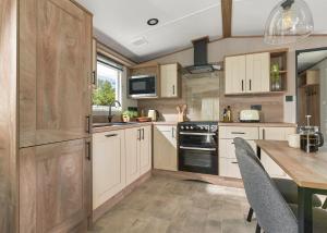 a kitchen with white cabinets and a table with chairs at Burtree Lakes Holiday Park in Bedale