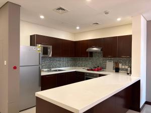 a kitchen with brown cabinets and a white refrigerator at Modern comfort in a compact spacious studio one or two bedroom retreats in Manama