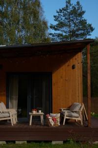 a cabin with a deck with two chairs and a table at MISI domek in Kadłubówka