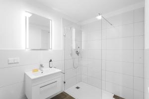 a white bathroom with a sink and a shower at Neben Forum Allgäu inkl. Balkon in Kempten +16 photos
