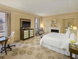une chambre avec un grand lit blanc et un bureau dans l'établissement Fairmont Hotel Vancouver, à Vancouver