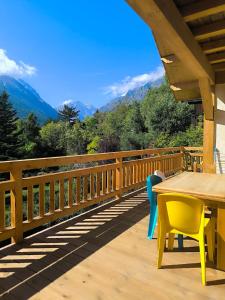 a wooden deck with a table and chairs and mountains at Magnifique chalet neuf Pelvoux Vallouise Puy Saint Vincent in Le Poët