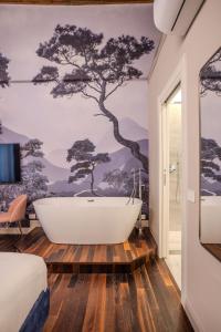 een badkamer met een ligbad en een boommuurschildering bij La Maison de Ville & Suite in Piacenza