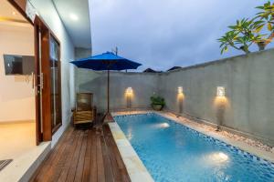 a swimming pool with a blue umbrella and a chair at Adi s Private Villa in Sukawati